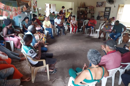 Um grupo de pessoas se senta em círculo em cadeiras de plástico em uma sala
