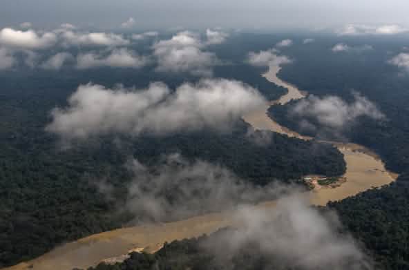 Fotografia aérea com nuvens e rio sinuoso passando pela floresta tropical