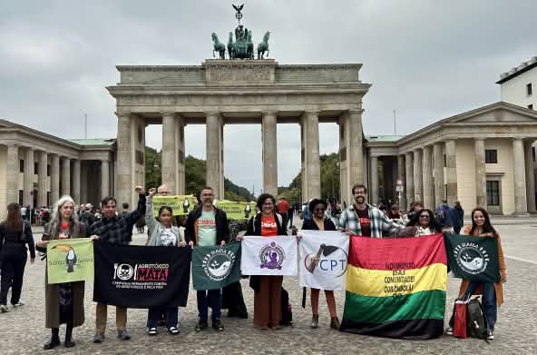 Grupo de 11 pessoas com faixas em frente ao Portão de Brandenburgo em Berlim
