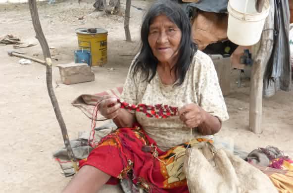 Mulher do povo Manjui sentada, trabalhando em um tecido à base de fibras vegetais