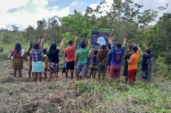 Um grupo de Ka'apor em frente a uma placa para seu território indígena de Alto Turiaçu