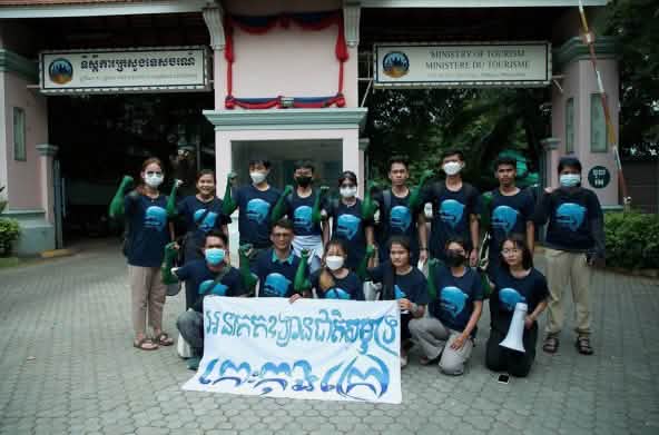 15 adolescentes em pé, à frente do prédio do Ministério do Turismo e a segurar, diante da câmera, uma faixa na qual consta: „Koh Kong Island deve se tornar parque nacional marítimo“