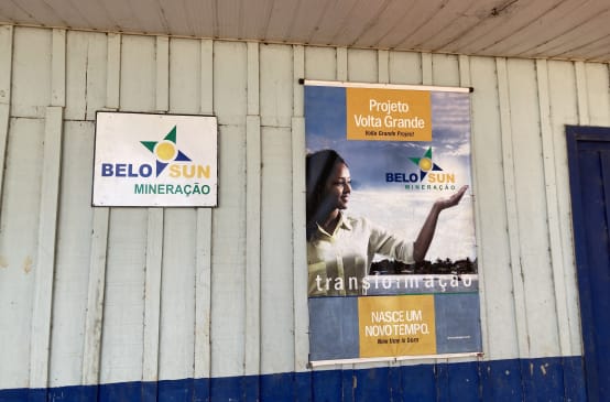 Uma placa da empresa de mineração Belo Sun e um pôster com propaganda da empresa na parede de uma cabana de madeira