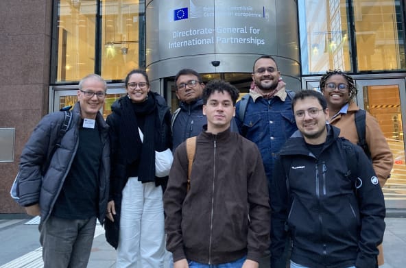 Foto de grupo de 7 pessoas à frente da entrada de um prédio da Comissão Européia em Bruxelas l