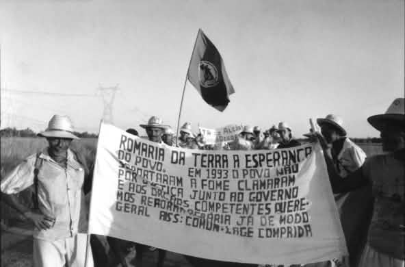 Trabalhadores rurais caminham segurando uma faixa em defesa do acesso à terra