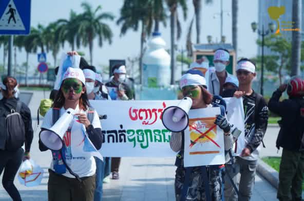 Grupo de jovens estudantes anda com megafone e cartazes por uma rua