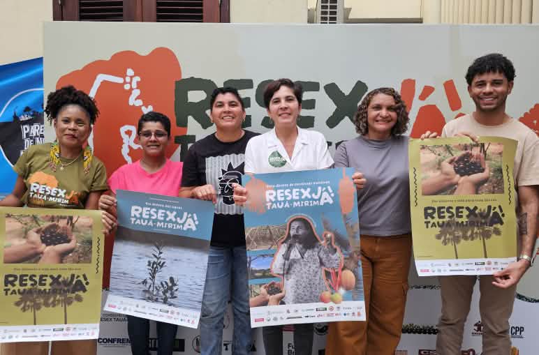 Grupo de seis pessoas seguram cartazes em apoio à Resex Tauá-Mirim