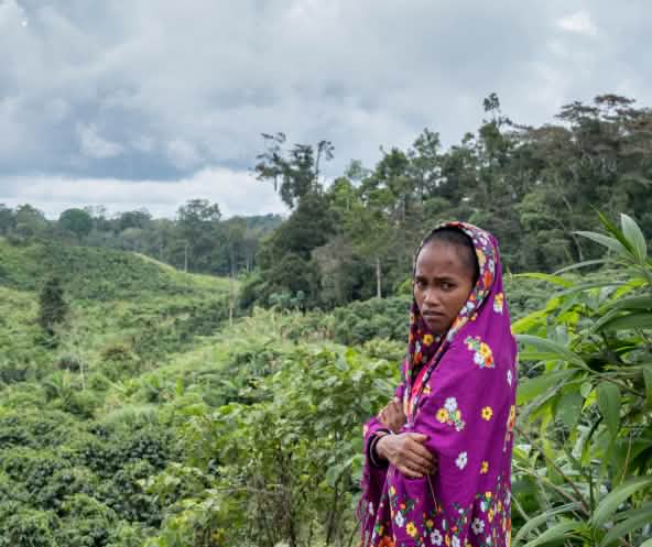 Mirivic Tarsila Danyan, coberta por um véu, em frente de área de floresta desmatada nas Filipinas