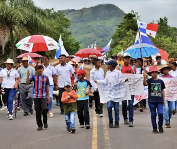 Manifestantes marcham com faixas, bandeiras e guarda-chuvas em uma rodovia no Panamá