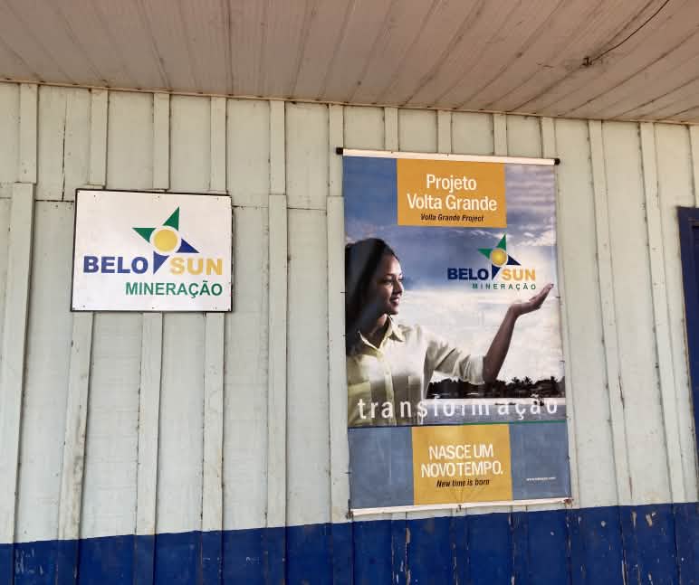 Propaganda da empresa mineradora Belo Sun na Vila de Ressaca Uma placa da empresa de mineração Belo Sun e um pôster com propaganda da empresa na parede de uma cabana de madeira