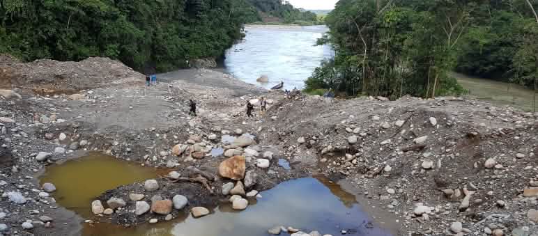 Sedimentos revirados e lago contaminado às margens de rio na floresta