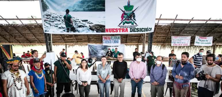 Cerimônia em uma aldeia na floresta tropical: Grupo de pessoas formando um círculo embaixo de uma faixa
