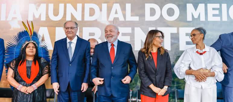 O Presidente Lula e o Vice Alckmin, junto com ministras e ministros, diante de um cartaz sobre o Dia Mundial do Meio-Ambiente