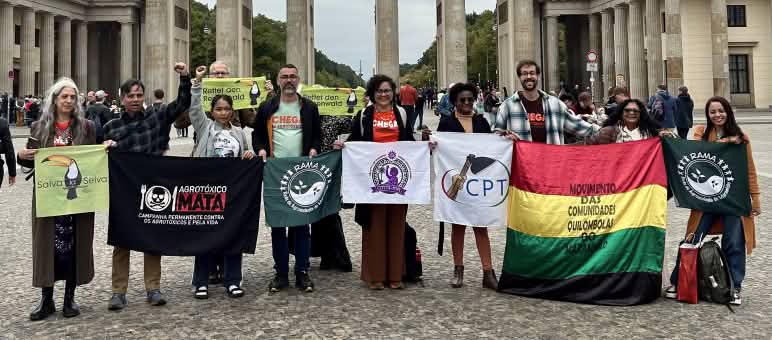 Grupo de 11 pessoas com faixas em frente ao Portão de Brandenburgo em Berlim