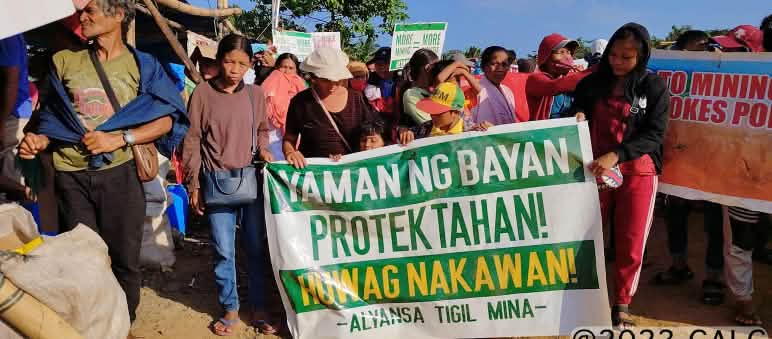 “Protejam a riqueza do povo! Nada de roubo! Aliança contra a mineração”: é o que se lê na faixa dos manifestantes Grupo de pessoas segura um cartaz, no qual se lê (traduzido): “Protejam a riqueza do povo! Nada de roubo! Aliança contra a mineração