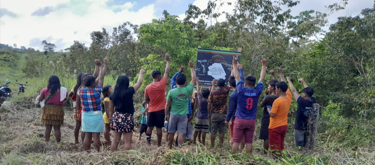 Um grupo de Ka'apor em frente a uma placa para seu território indígena de Alto Turiaçu