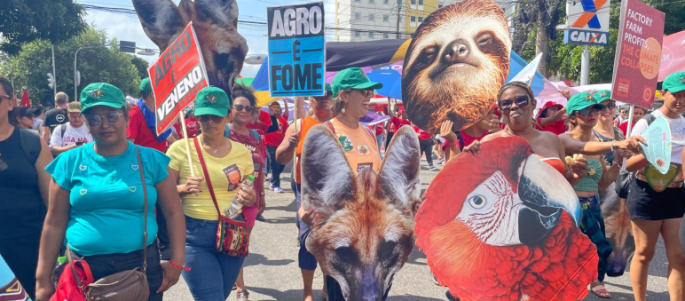 Manifestantes carregando grandes cartazes com cabeças de animais