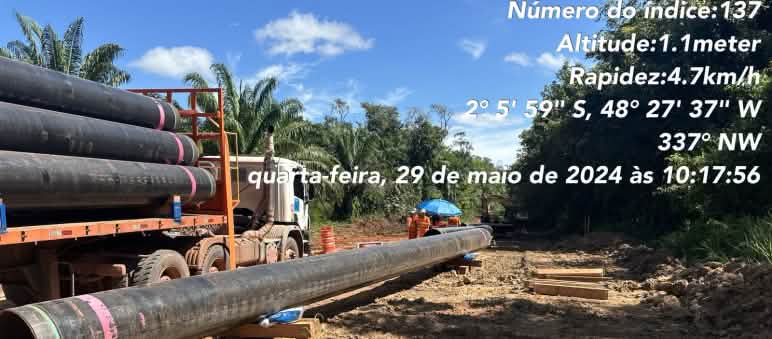 Um caminhão com seções de tubulação de dutos e seções de tubulação já colocadas no chão em um local de construção na floresta tropical