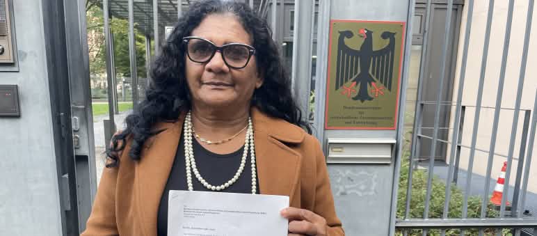 A quilombola Marli Borges com uma carta, à frente do portão de entrada do Ministério do Desenvolvimento Econômico e Cooperação (BMZ), em Berlim