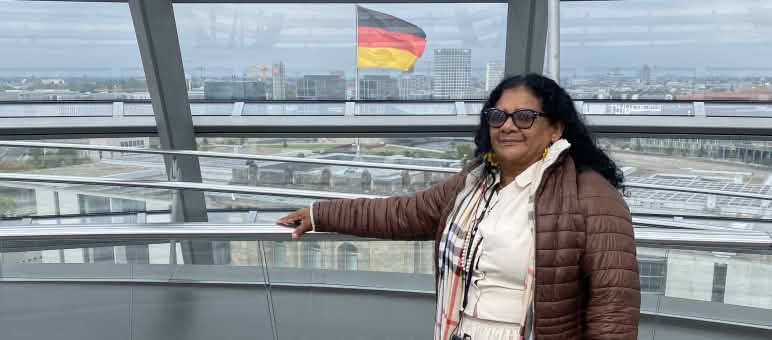 A quilombola Marli Borges na cúpula de vidro do Bundestag com a bandeira alemã ao fundo