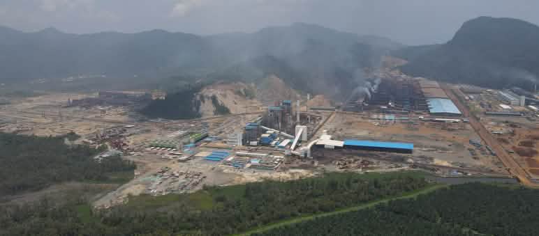 Vista aérea de um complexo industrial soltando fumaça na ex-floresta tropical, agora devastada.