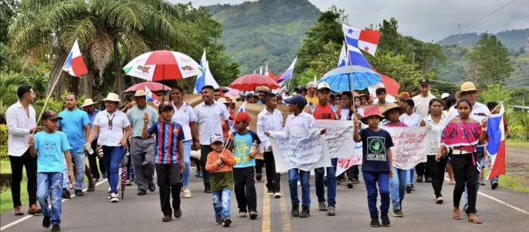 Manifestantes marcham com faixas, bandeiras e guarda-chuvas em uma rodovia no Panamá