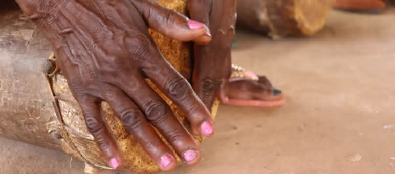 Duas mãos femininas tocando tambor. A pele é negra e as unhas são pintadas de rosa