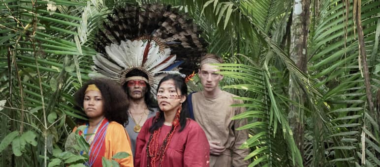 Cena da peça de teatro "Antígona na Amazônia" Atrizes e atores da peça de teatro “Antígona na Amazônia” em pé, na floresta amazônica