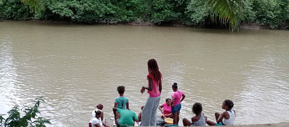 Grupo de mulheres às margens de um rio turvo na floresta tropical