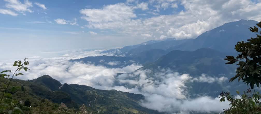 Paisagem montanhosa na área do Rio Blanco, com nuvens brancas no solo e no céu