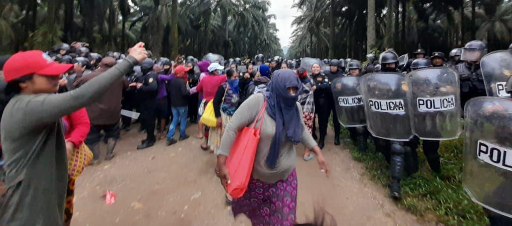 No lado esquerdo, um grupo maia protesta, enquanto no lado direito unidades policiais munidos de capacetes protetores e escudos partem para cima dos povos originários das florestas