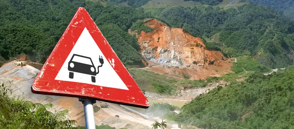 (Montagem) Placa de trânsito com carro elétrico em frente de uma mina de lavra a céu aberto (Montagem de foto) Placa de trânsito com carro elétrico em frente de uma mina de lavra a céu aberto