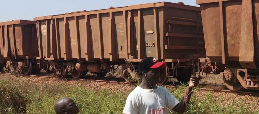Trem de carga, e diante dele, um menino e um homem