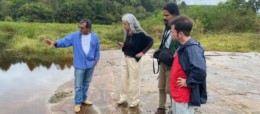 Quatro pessoas observam um corpo de água da margem