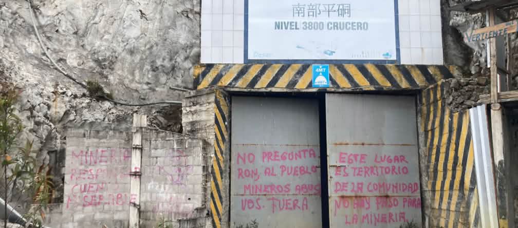 Portão fechado de acesso para uma galeria com inscrições de protesto