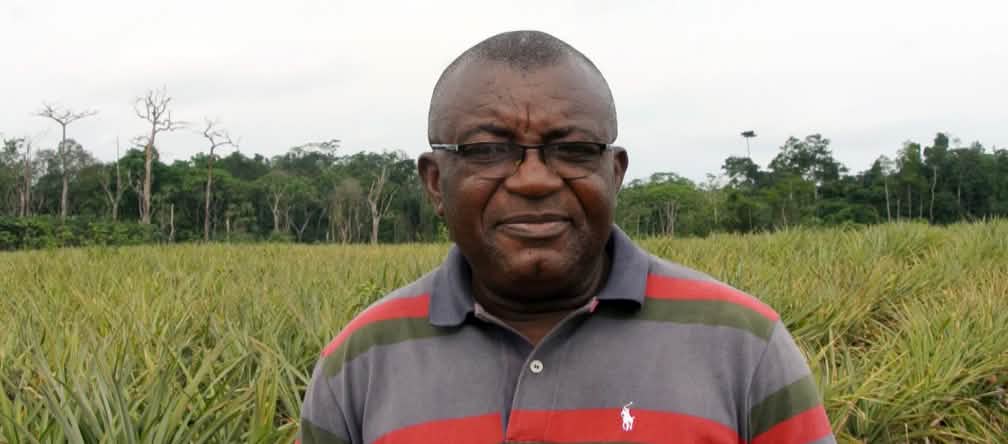 Odey Oyama luta contra plantações de abacaxi no Parque Nacional Cross River Odey Oyama à frente de uma plantação de abacaxi