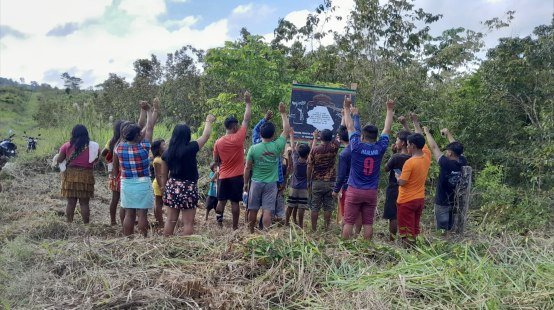 Um grupo de Ka'apor em frente a uma placa para seu território indígena de Alto Turiaçu