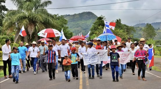 Manifestantes marcham com faixas, bandeiras e guarda-chuvas em uma rodovia no Panamá