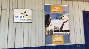 Uma placa da empresa de mineração Belo Sun e um pôster com propaganda da empresa na parede de uma cabana de madeira