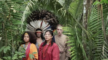 Atrizes e atores da peça de teatro “Antígona na Amazônia” em pé, na floresta amazônica