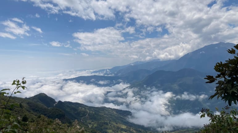 Paisagem montanhosa na área do Rio Blanco, com nuvens brancas no solo e no céu