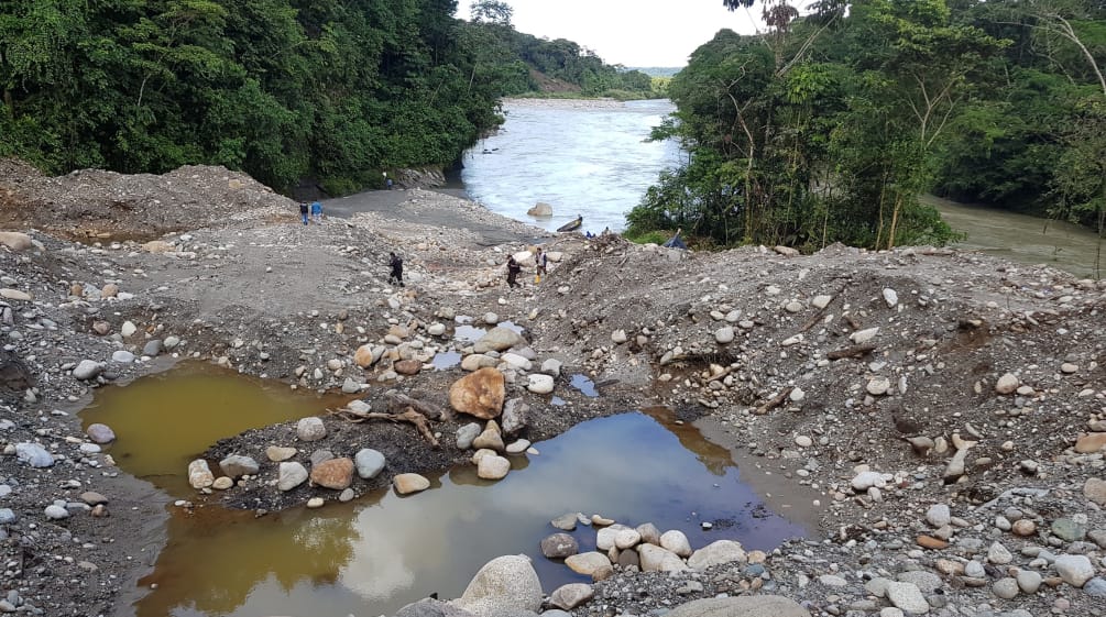 Sedimentos revirados e lago contaminado às margens de rio na floresta