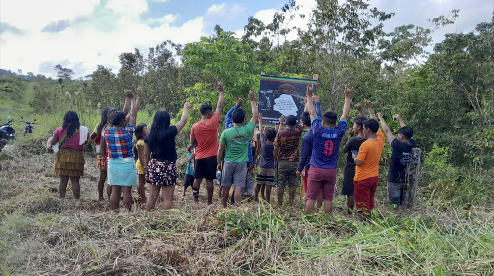 Um grupo de Ka'apor em frente a uma placa para seu território indígena de Alto Turiaçu