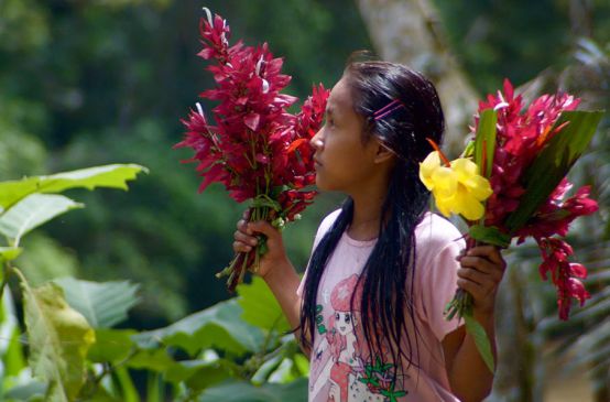 Uma garota do povo Kichwa em Sarayaku com flores nas mãos