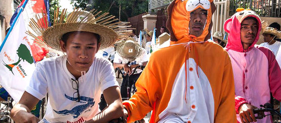 Manifestantes em fantasias de animais em bicicletas no Camboja