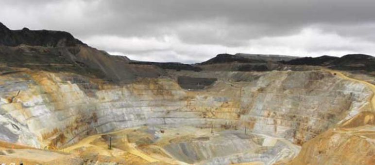 Os estragos da mineração a céu aberto Agricultores olham para uma mina de ouro