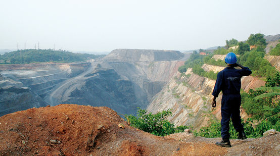 Um trabalhador em frente a uma mina a céu aberto