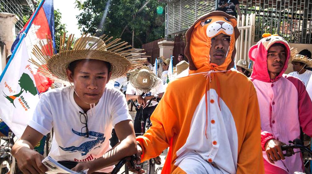 Manifestantes em fantasias de animais em bicicletas no Camboja